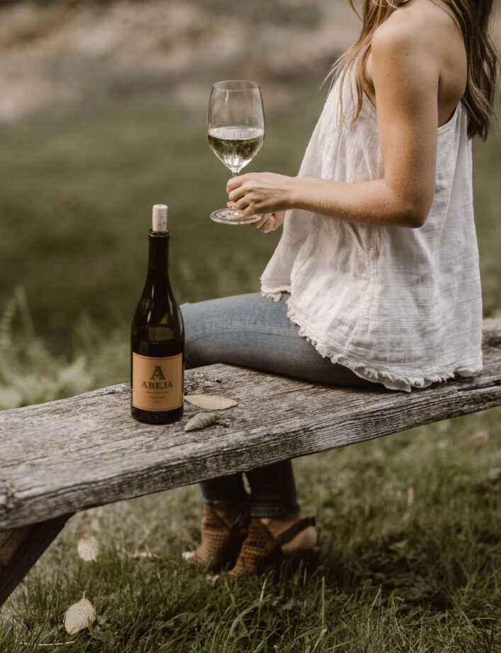 Woman Sitting on Bench with Wine at Abeja