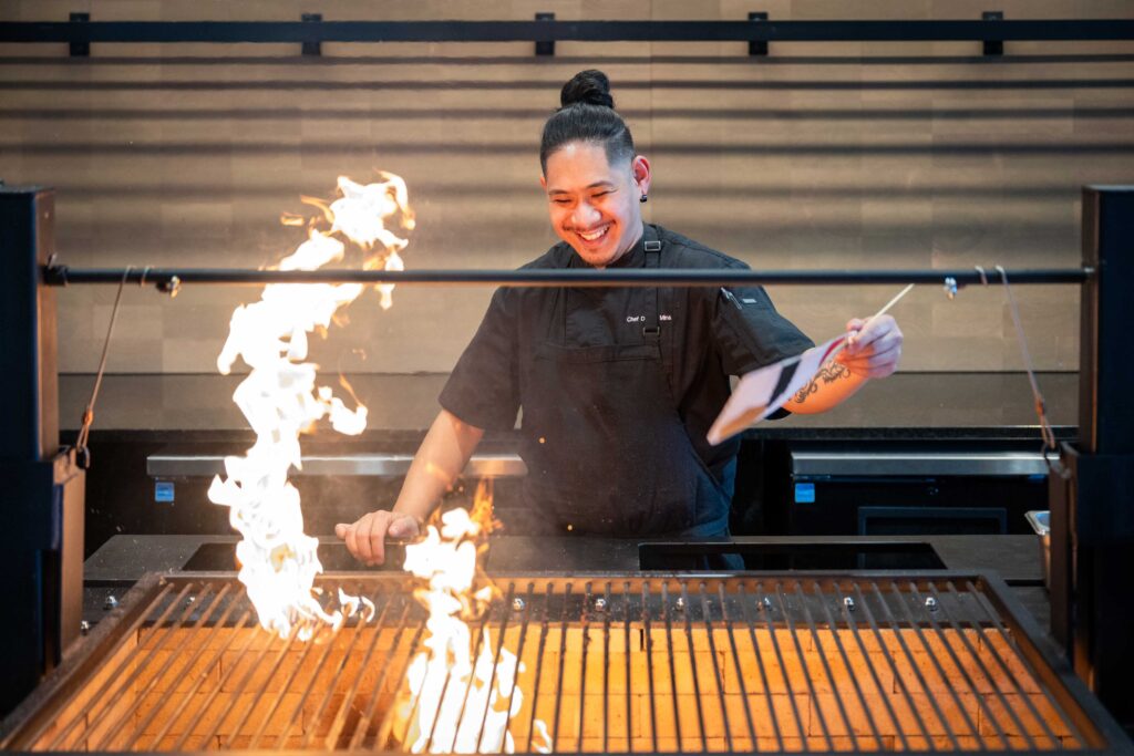 Chef preparing food over an open flame grill